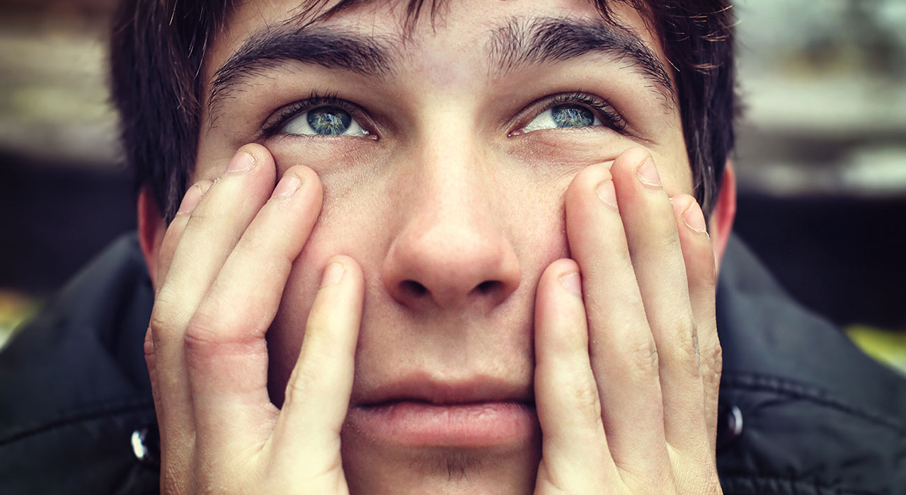 boy sitting with his hands on his face